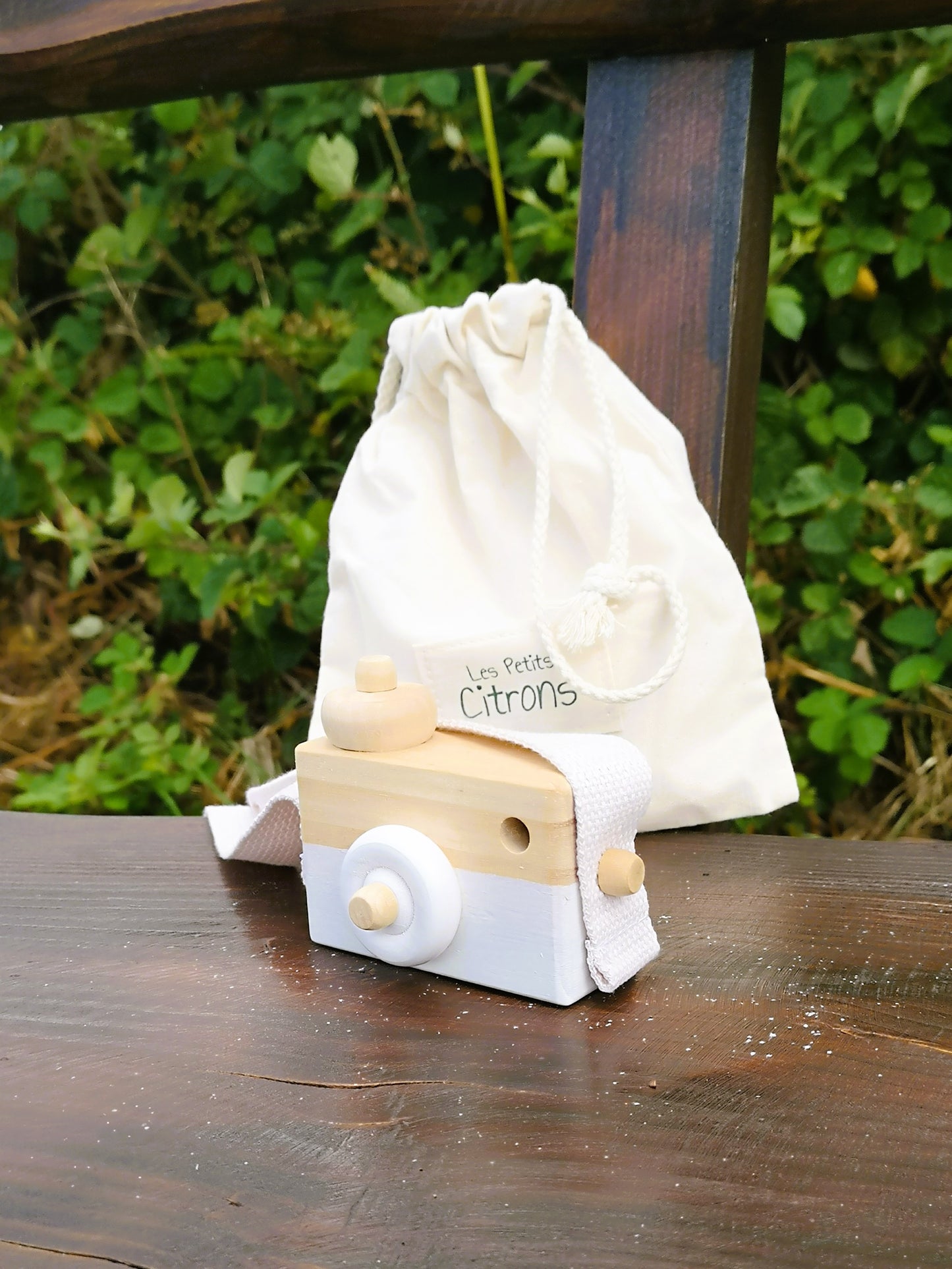 Weiße Holzkamera am Gürtel eines Kindes in Sommerwiese – nachhaltiges Accessoire für kleine Abenteurer