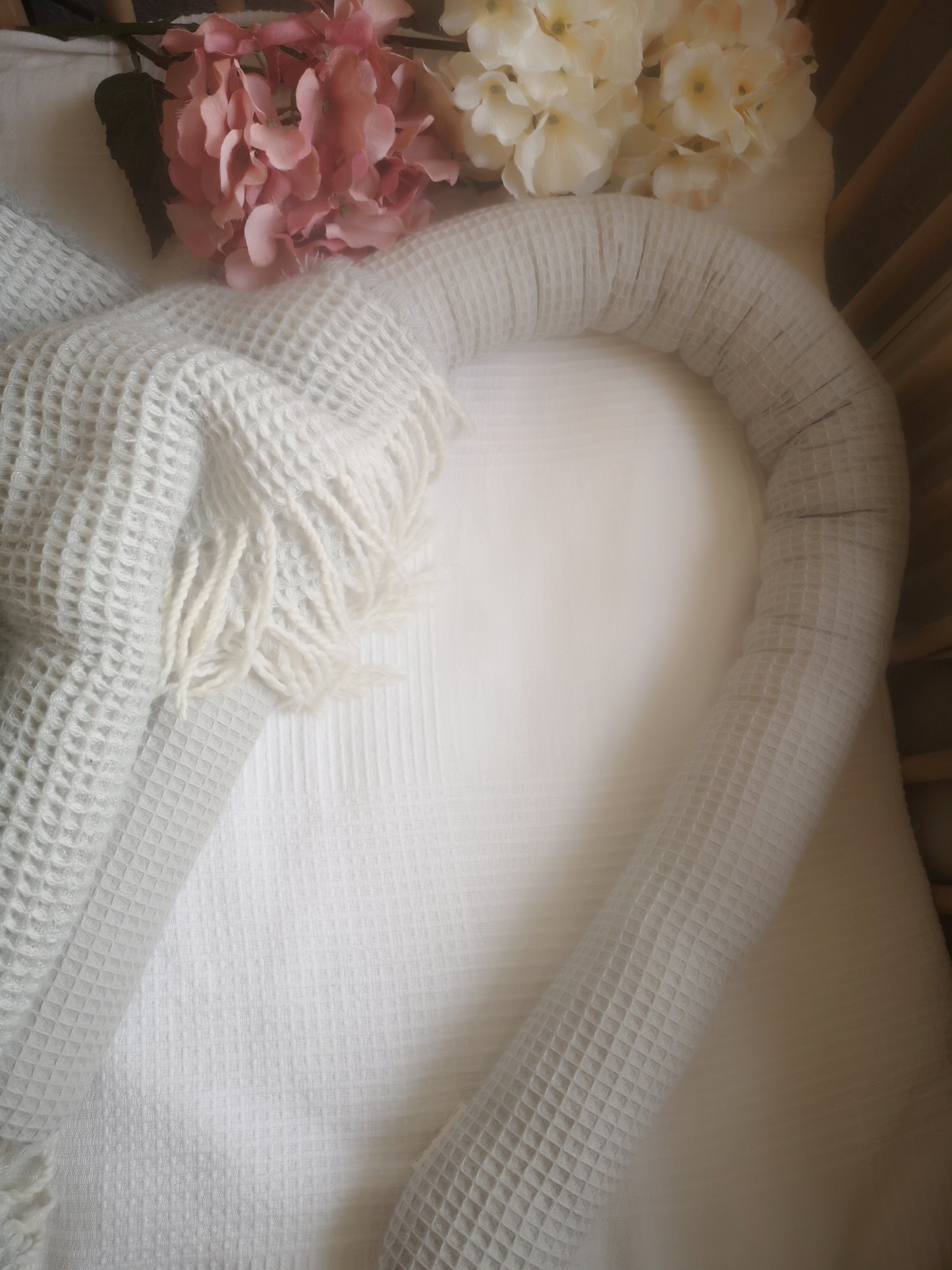 Nahaufnahme eines weichen Babynestchens mit Waffelstruktur und floraler Deko – ideal für Neugeborene