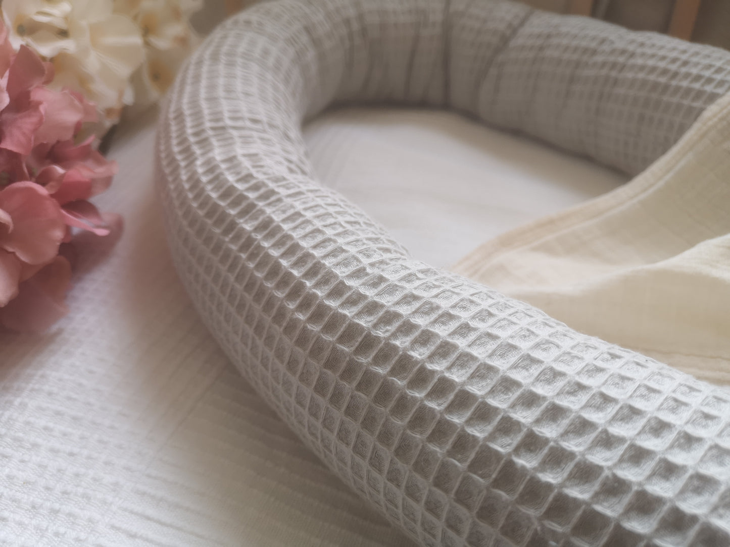 Detailaufnahme eines leeren Baby-Nestchens aus grauem Waffelpiqué-Stoff auf hellem Untergrund