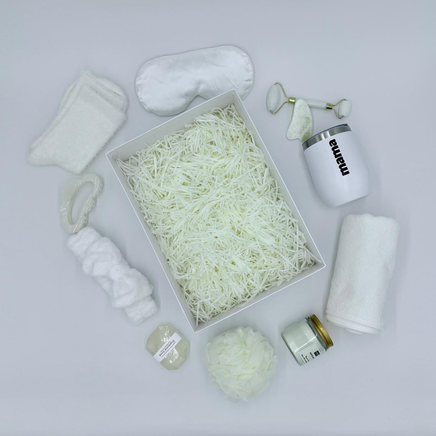 Weiße Box mit Wellnessprodukten wie Duschwamm, Stirnband und Handtuch