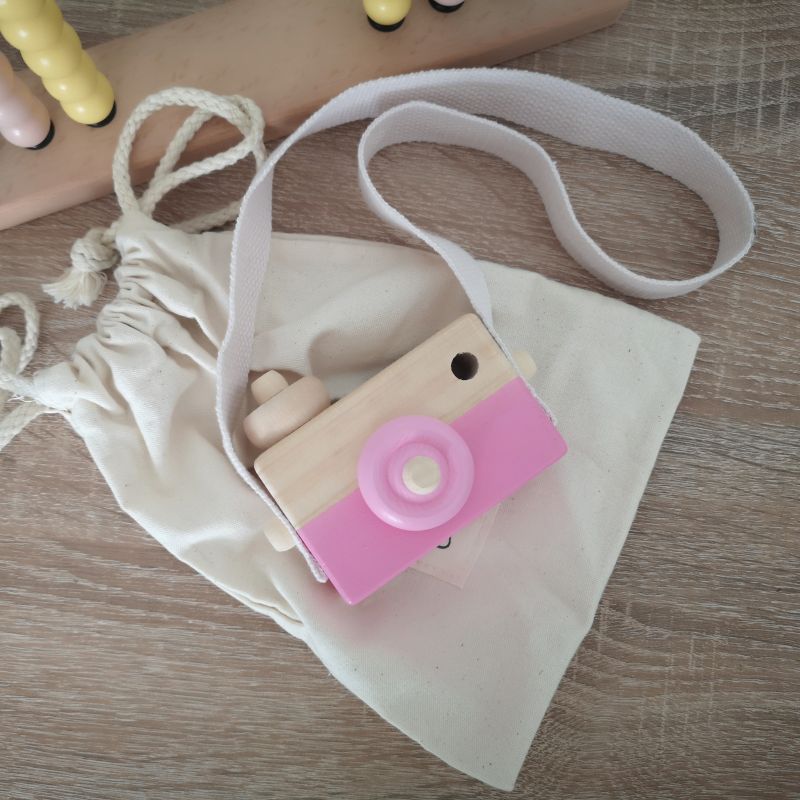 Sommerliche Szene mit Kinder-Holzkamera und Sonnenhut auf Wiese – ideales Motiv für Onlineshop