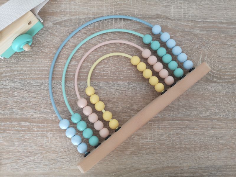 Pastellfarbener Holz-Abakus in Regenbogenform auf Holzuntergrund, Montessori-inspiriertes Lernspielzeug