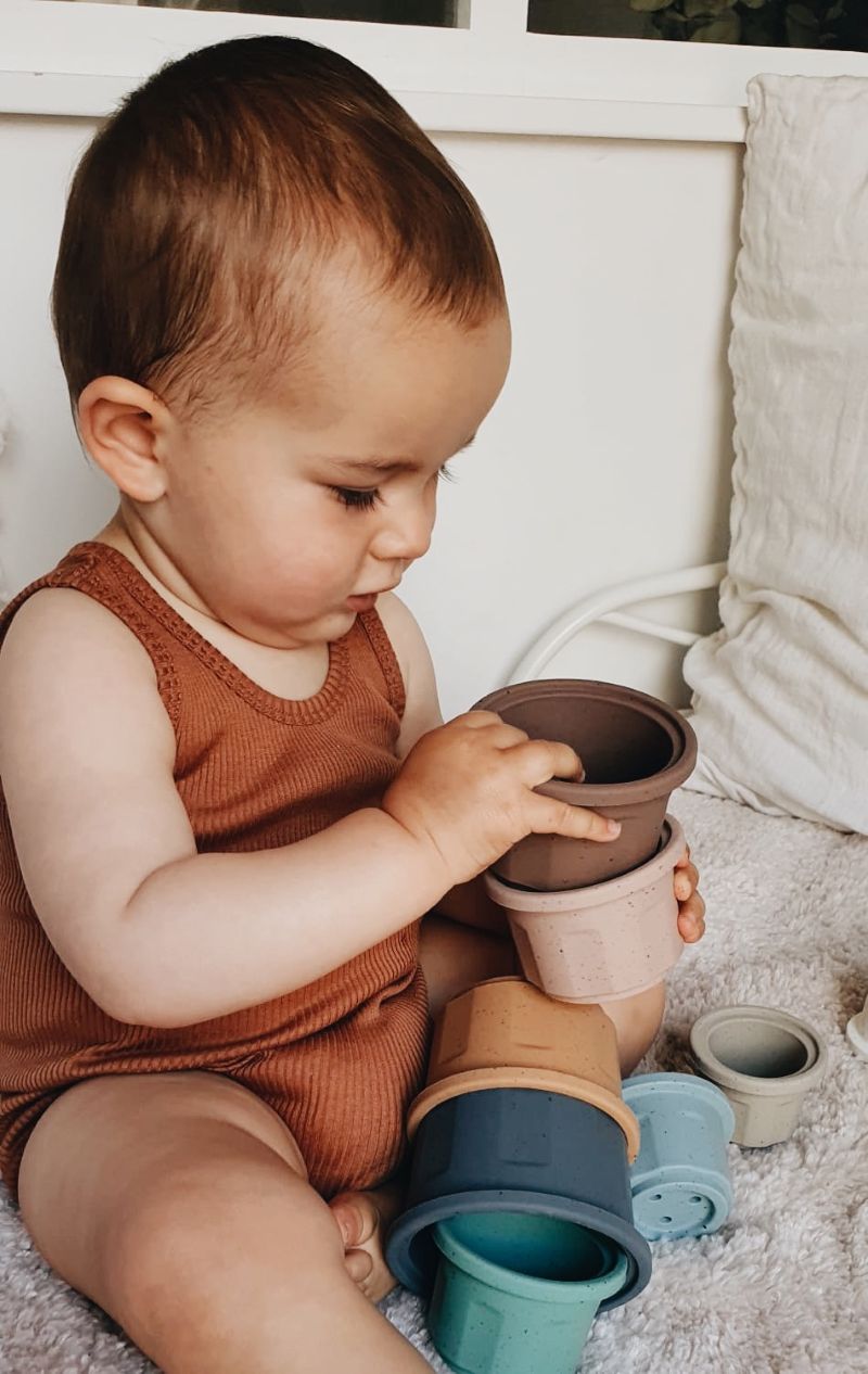Baby spielt mit stapelbaren Silikonbechern in Naturfarben – sensorisches Motorikspielzeug ab 6 Monaten