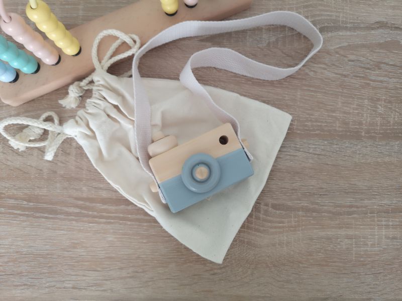 Minimalistische Holzspielkamera mit Band, dekorativ aufgehängt – robust und kindgerecht verarbeitet